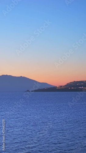 Sunset in Mykonos island, Greece with yachts in the harbor and colorful waterfront houses of Little Venice romantic spot on sunset illuminated in evening. Mykonos townd, Greece. Camera pan photo