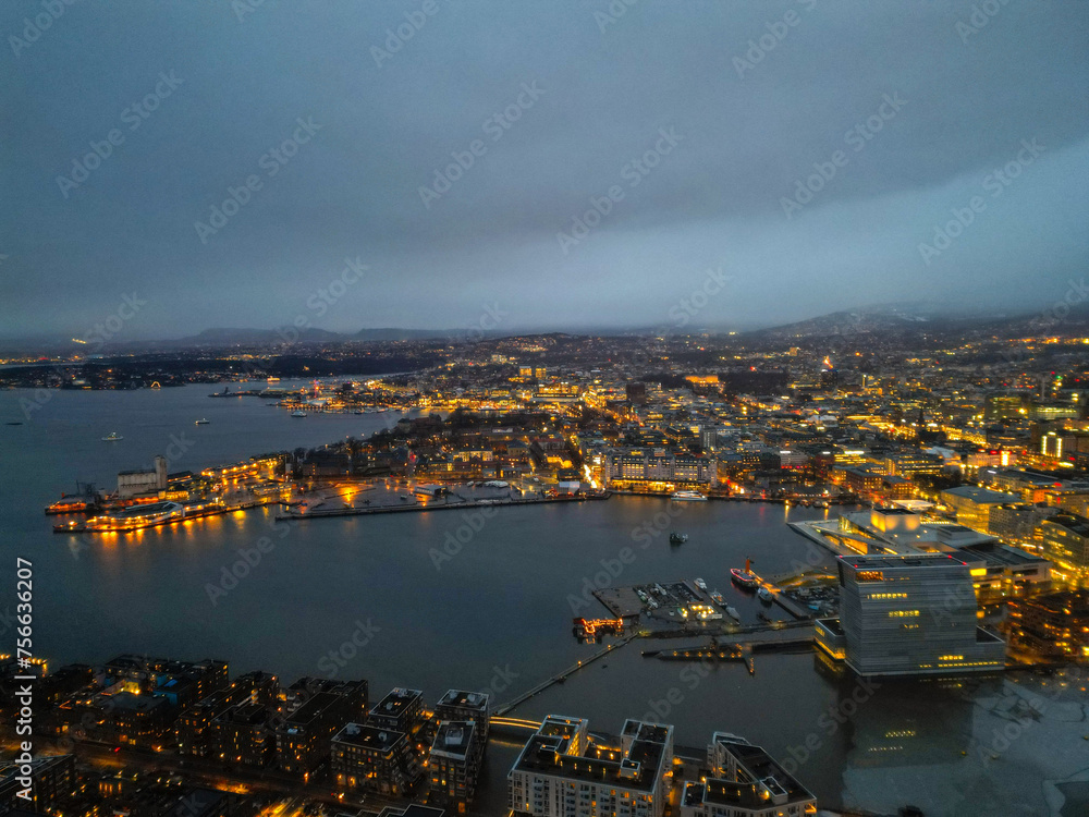 Naklejka premium Top aerial view of Oslo city in Norway at evening time. Panorama view of city with modern architecture and transportation. The fjord city with seashore and icebergs. The lighting time of capital city.