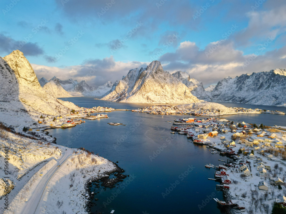 Aerial view of Lofoten island Norway. The winter season of sunrise fishing village of Reine with snowscape mountain peak reflect on water. Norway with red rorbu houses. With falling snow in winter. Aerial view of Lofoten island Norway. The winter season of sunrise fishing village of Reine with snowscape mountain peak reflect on water. Norway with red rorbu houses. With falling snow in winter.