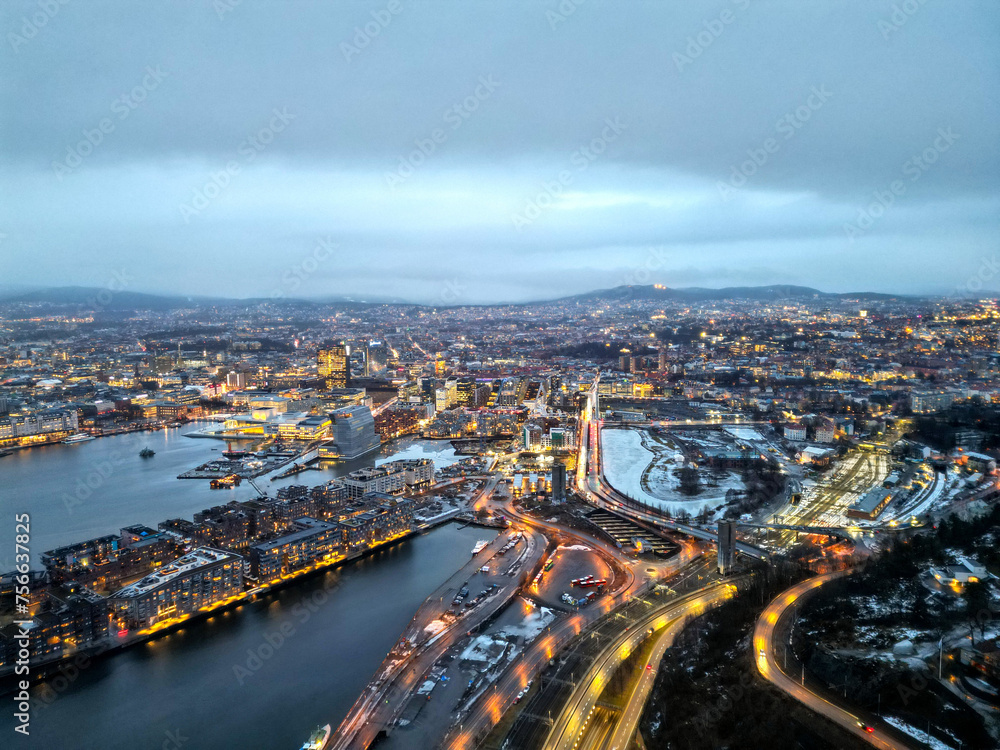 Top aerial view of Oslo city in Norway at evening time. Panorama view of city with modern architecture and transportation. The fjord city with seashore and icebergs. The lighting time of capital city.