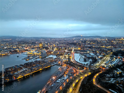 Top aerial view of Oslo city in Norway at evening time. Panorama view of city with modern architecture and transportation. The fjord city with seashore and icebergs. The lighting time of capital city.