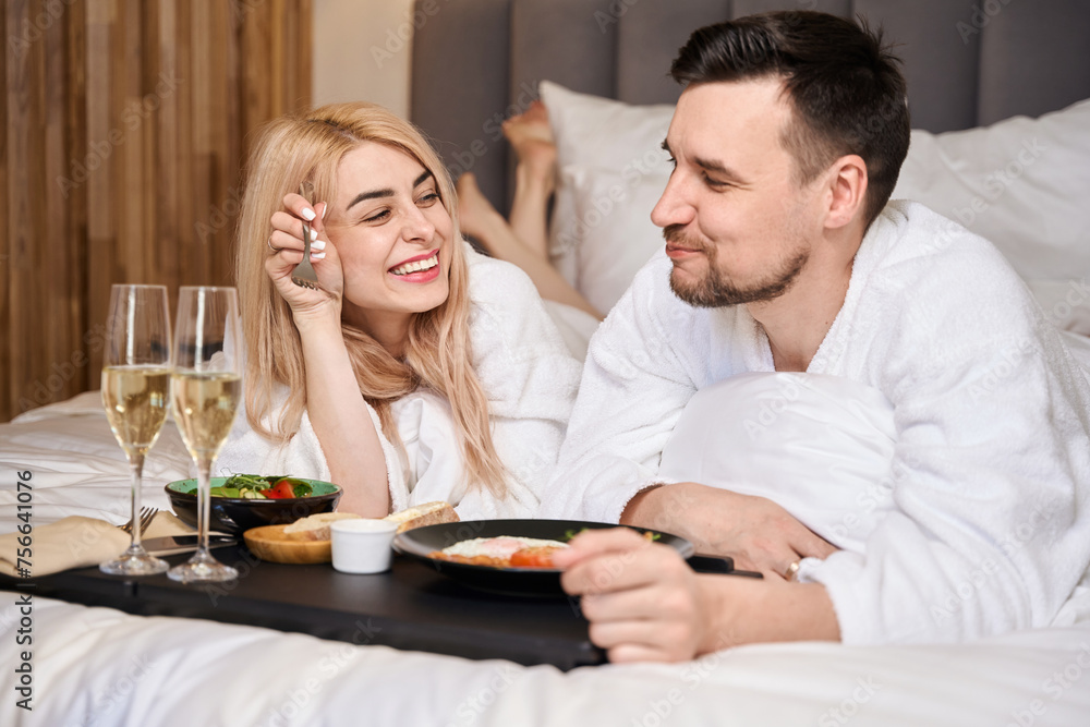 Young married couple communicates over breakfast in bed Young married couple communicates over breakfast in bed