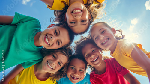 High-angle shot of a group of children forming a circle and looking up towards the camera with smiling faces.