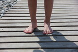 Bare feet of a child close-up on a wooden board on the beach