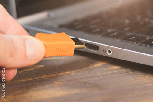 Man is insert the cable HDMI into the Port for information transfer. Close up, modern technology. Side panel on a laptop. Different ports for connection. photo