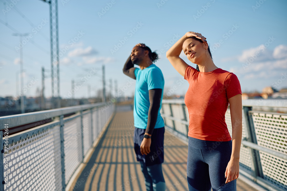 Athletic couple doing stretching exercises while working out outdoors.