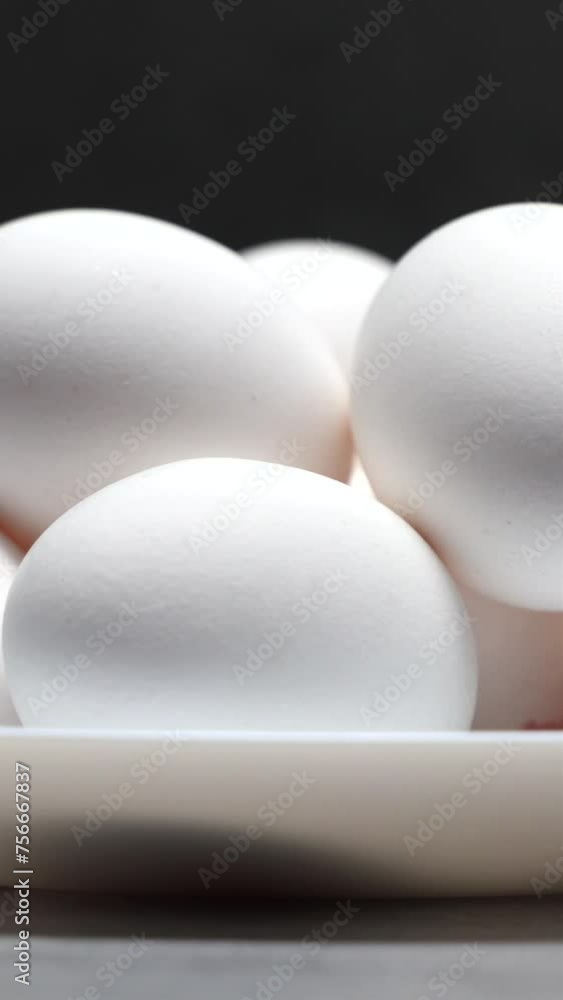 White Chicken Eggs On A White Plate On A Dark Background. Slider Shot. Vertical. White Chicken Eggs On A White Plate On A Dark Background. Slider Shot. Vertical.