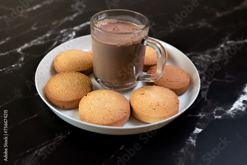 Cup of hot chocolate and cookies on a white plate on a black marble background photo