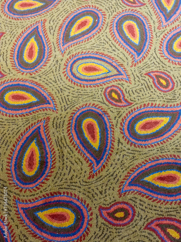 A carpet with a paisley pattern is shown in a tan color