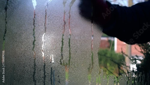 Hand wiping condensation from window 