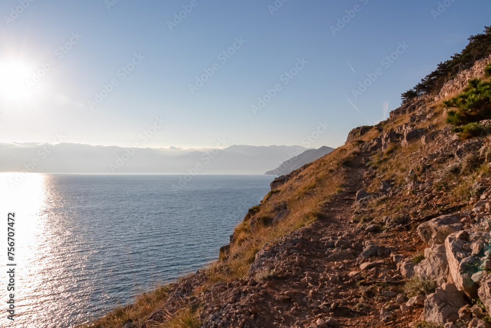 Coastal hiking trail along steep cliffs and mountains near tourist town Baska, Krk island, Primorje-Gorski Kotar, Croatia, Europe. Majestic coastline of Adriatic Mediterranean Sea in Kvarner Bay. Hike