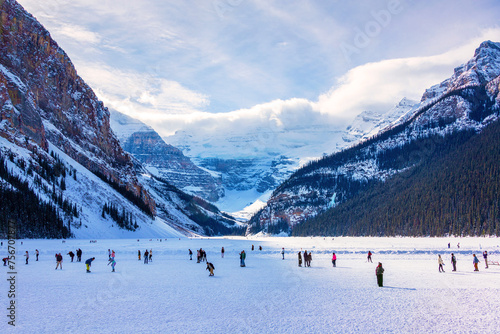Visitors skating on frozen Lake Louise in Winter against the backdrop of the stunning Victoria Glacier
