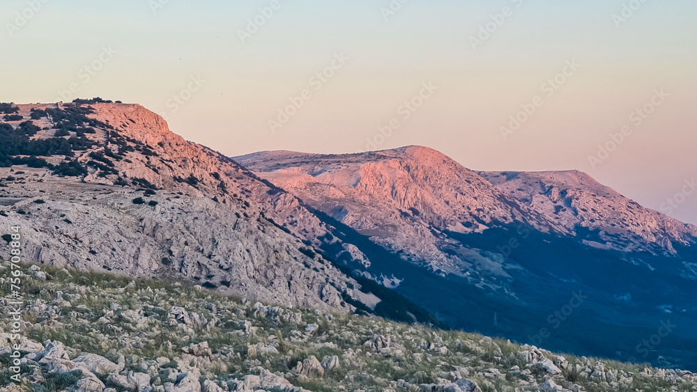 Panoramic view majestic mountain ranges around coastal town Baska, Krk Otok, Primorje-Gorski Kotar, Croatia, Europe. Hiking on deserted barren terrain. Alpine landscape. Vibrant coloured sky. Tranquil