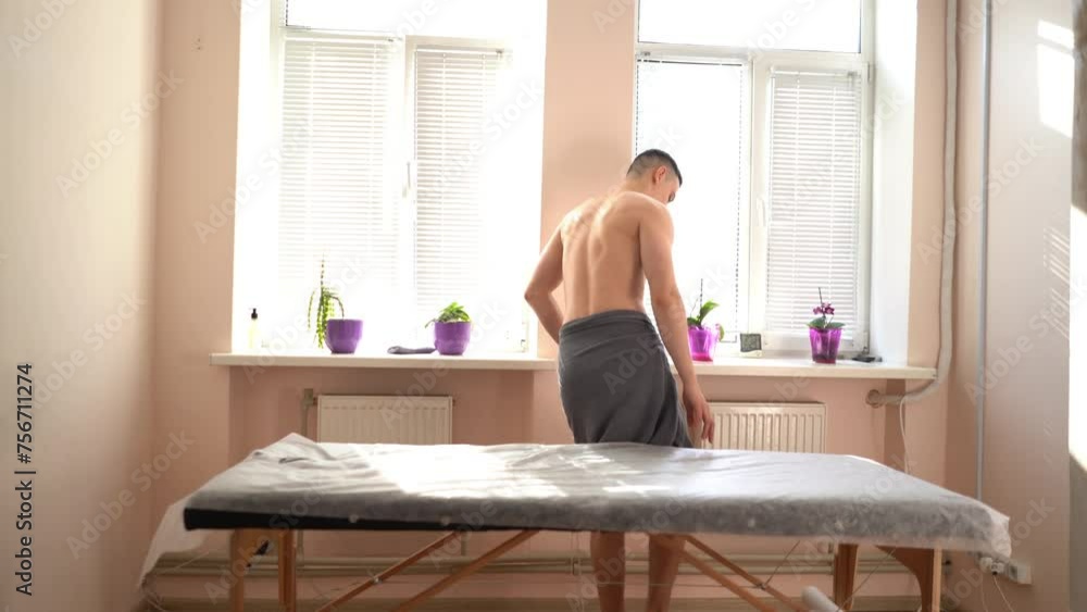 a young handsome sexy man with a naked torso undergoing a massage procedure in a sunny, bright room. The masseur presses the client's chest muscles and facial skin with his hands close-up a young handsome sexy man with a naked torso undergoing a massage procedure in a sunny, bright room. The masseur presses the client's chest muscles and facial skin with his hands close-up