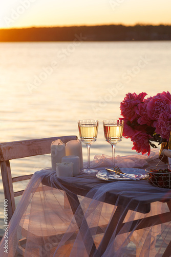 Romantic sunset dinner on the beach. Table honeymoon set for two with luxurious food, glasses of champagne drinks in a restaurant with sea view. Summer love, romance date on vacation concept.