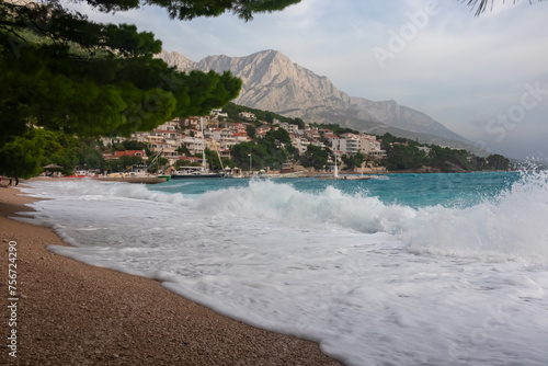 Empty beach Plaza Soline in idyllic coastal town Brela, Makarska Riviera, Dalmatia, Croatia. Scenic view of majestic coastline of Adriatic Mediterranean Sea. Dramatic waves and Biokovo nature park photo