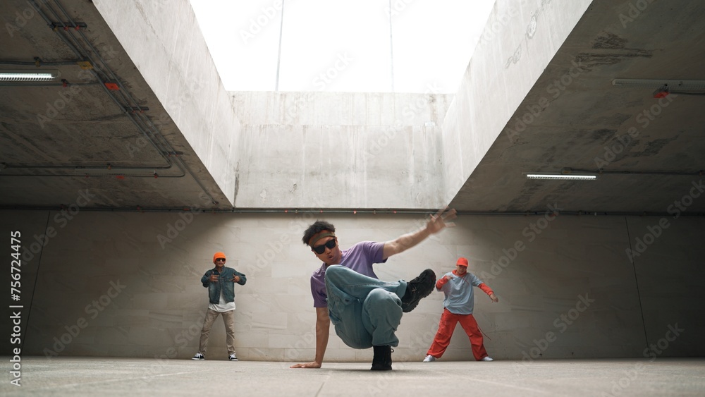 Group of stylish hipster perform dancing together in building. Happy break dancer enjoy moving to hip hop music with freestyle dance surrounded by street dancer team. Outdoor sport 2024. Sprightly.