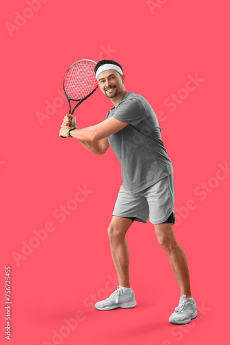 Sporty young man playing tennis on red background © Pixel-Shot