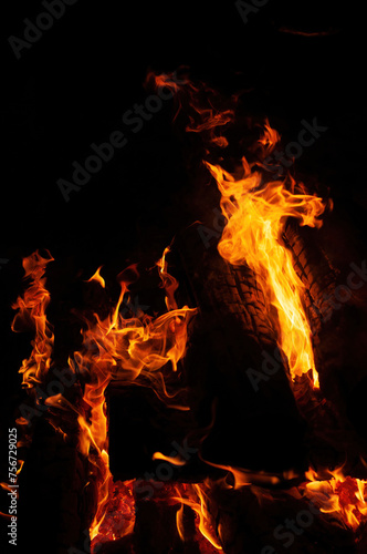 A mesmerizing close up of bonfire in nature, with flames dancing against black background. heat and flickering flames create captivating event, reminiscent of cozy fireplace or campfire