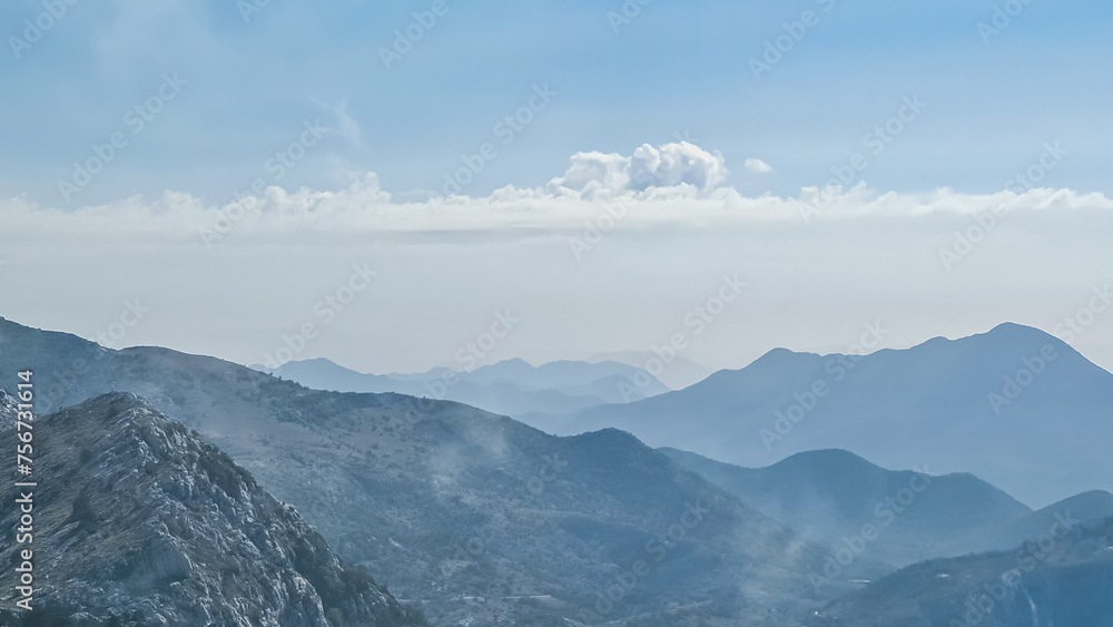 Panoramic view of mystical fog covered mountain ranges of Biokovo nature park near Makarska, Dalmatia, Croatia. Scenic hiking trail in karst landscape in Dinaric Alps in summer. Wanderlust atmosphere