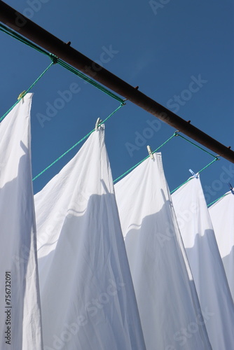 white bed linen hanging outside on a line © Marie