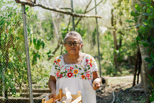 Portrait of an indigenous woman looking at the camera holding a basket of tomatoes in a harvest field in Mexico.