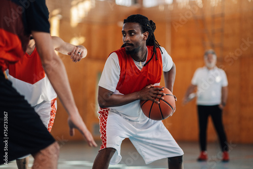Interracial sportsman is defending a ball during basketball training.