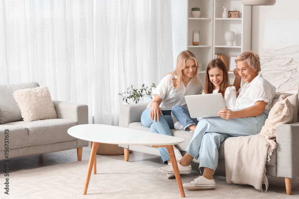 Little girl with her mom and grandmother using laptop on sofa at home Little girl with her mom and grandmother using laptop on sofa at home