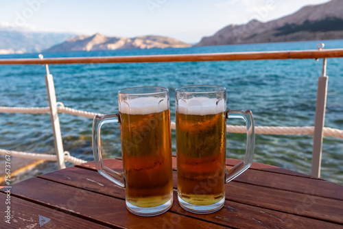 Fototapeta Naklejka Na Ścianę i Meble -  Drinking beer at a beach bar in idyllic coastal town Baska, Krk Island, Primorje-Gorski Kotar, Croatia, Europe. Majestic coastline of Mediterranean Adriatic in summer. Vacation in tropical paradise