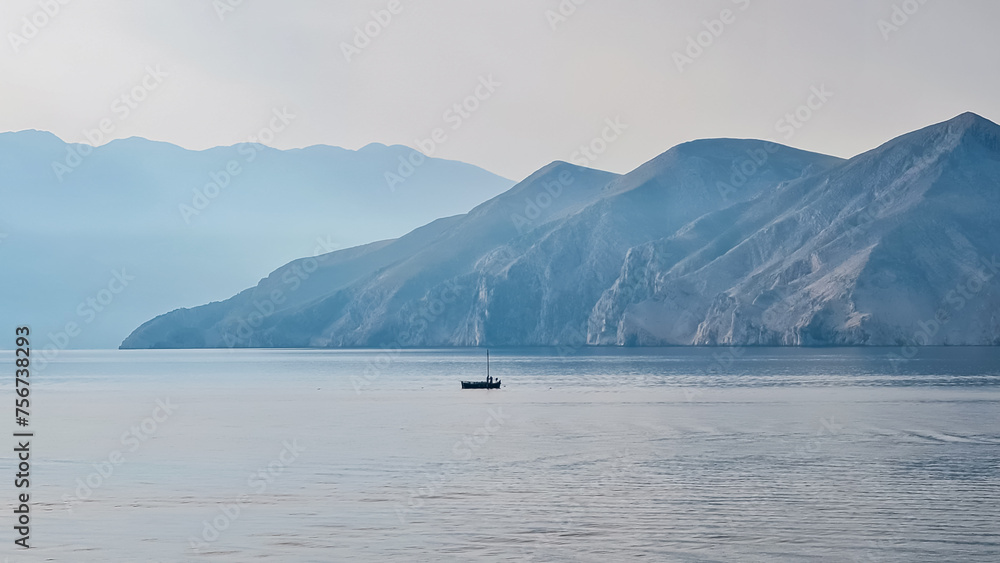 Small sailing boat cruising around archipelago near idyllic coastal town Baska, Krk Island, Primorje-Gorski Kotar, Croatia, Europe. Majestic coastline of Mediterranean Adriatic. Tranquil atmosphere