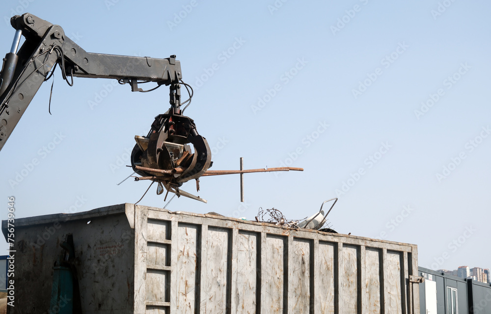 Crane grabber loading a truck with metal scrap. Metal waste on the junkyard. Crane grabber loading a truck with metal scrap. Metal waste on the junkyard.