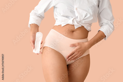 Young woman in menstrual panties with pad on beige background, closeup