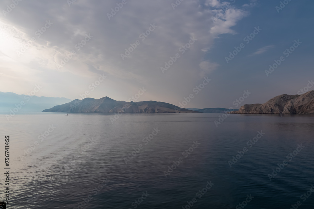 Scenic sunrise view of deserted island Prvic seen from beach in coastal town Baska, Krk Otok, Primorje-Gorski Kotar, Croatia, Europe. Majestic coastline of Mediterranean Adriatic Sea in Kvarner bay Scenic sunrise view of deserted island Prvic seen from beach in coastal town Baska, Krk Otok, Primorje-Gorski Kotar, Croatia, Europe. Majestic coastline of Mediterranean Adriatic Sea in Kvarner bay