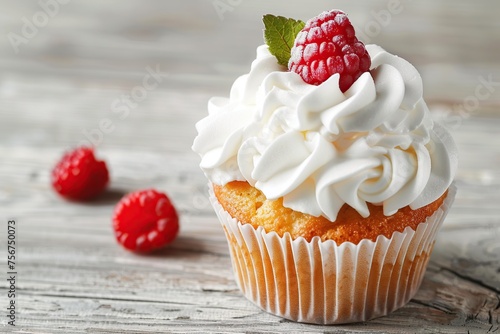 Tasty cupcake with butter cream and ripe raspberry on wooden table