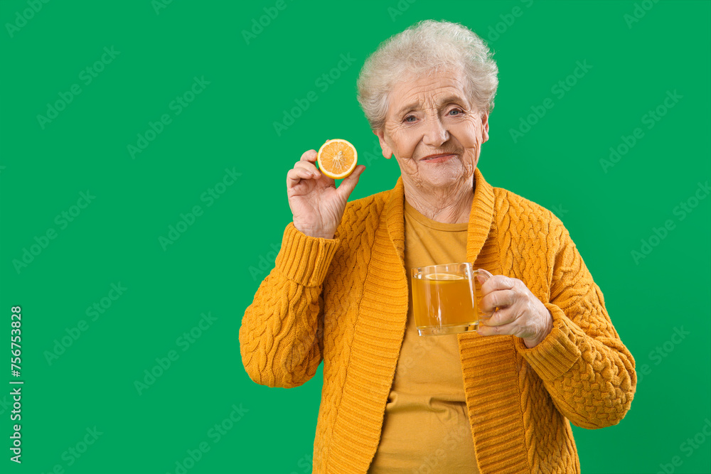 Senior woman with lemon and glass cup of tea on green background Senior woman with lemon and glass cup of tea on green background