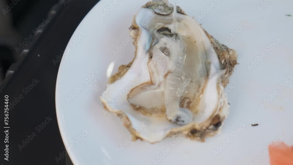 Squeezing lemon juice over raw oyster in a plate. Preparing seafood for eating. Top view. Healthy diet food Squeezing lemon juice over raw oyster in a plate. Preparing seafood for eating. Top view. Healthy diet food