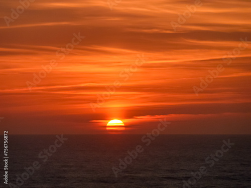 Watching romantic sunset overlooking the calm waters of the sea in Ericeira, Portugal, Europe. Looking at majestic Atlantic Ocean. Serene tranquil vacation. Empty tropical landscape in summer