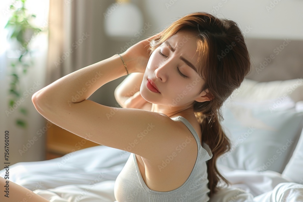Young Asian Woman Experiencing a Painful Headache in a Cozy Bedroom Setting at Dawn