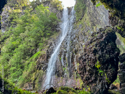 Looking through rocky cave on majestic waterfall Cascata Risco along idyllic Levada walk 25 fountains in evergreen subtropical Laurissilva forest of Rabacal  Madeira island  Portugal  Europe. Paradise