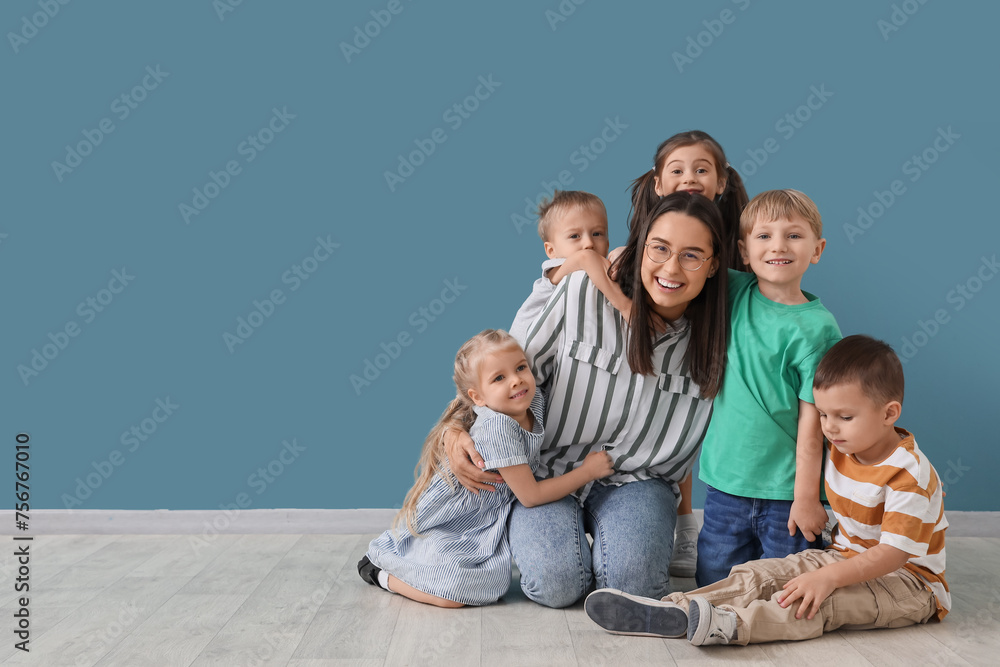 Little children hugging nursery teacher near blue wall Little children hugging nursery teacher near blue wall