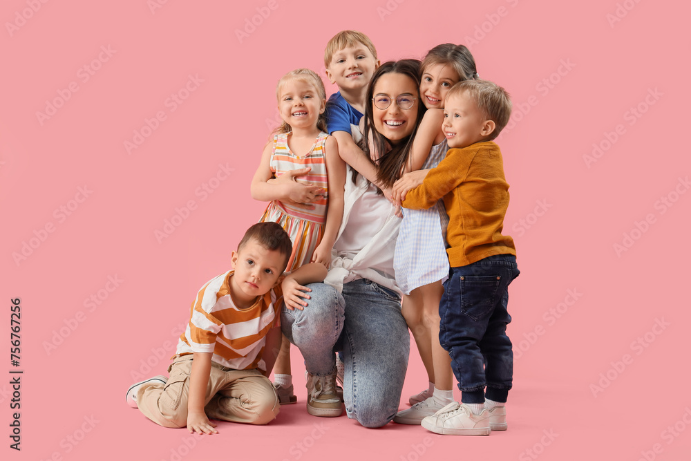 Little children hugging nursery teacher on pink background