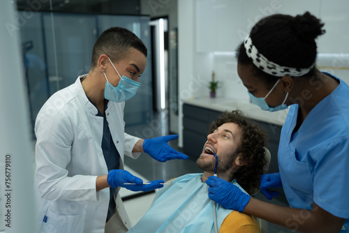 Female dentist and an intern communicating with a patient during the procedure.