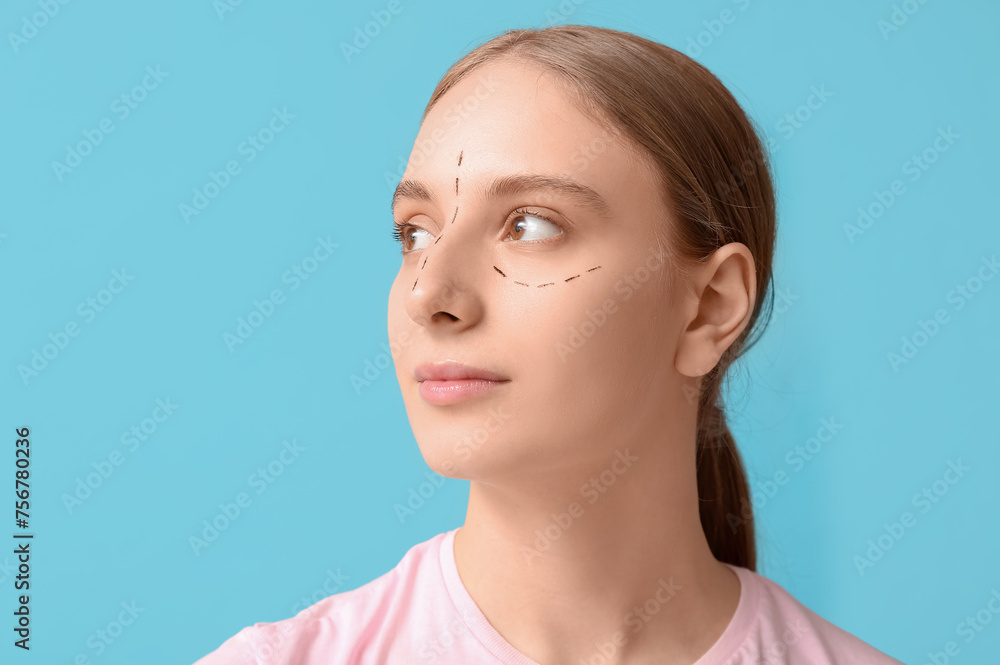 Young woman with marks on her face against blue background. Blepharoplasty concept Young woman with marks on her face against blue background. Blepharoplasty concept