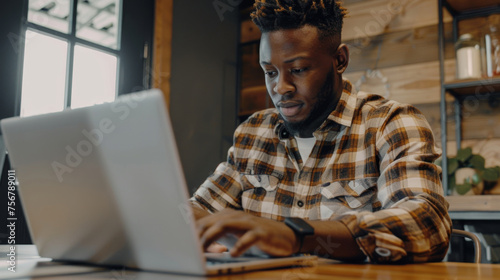 Intently focused African man using his laptop in a bright modern cafe setting