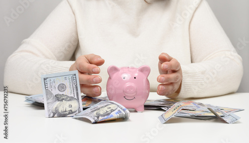 Pink ceramic piggy bank and woman with American paper money. Wealth concept, bargain, accumulation.