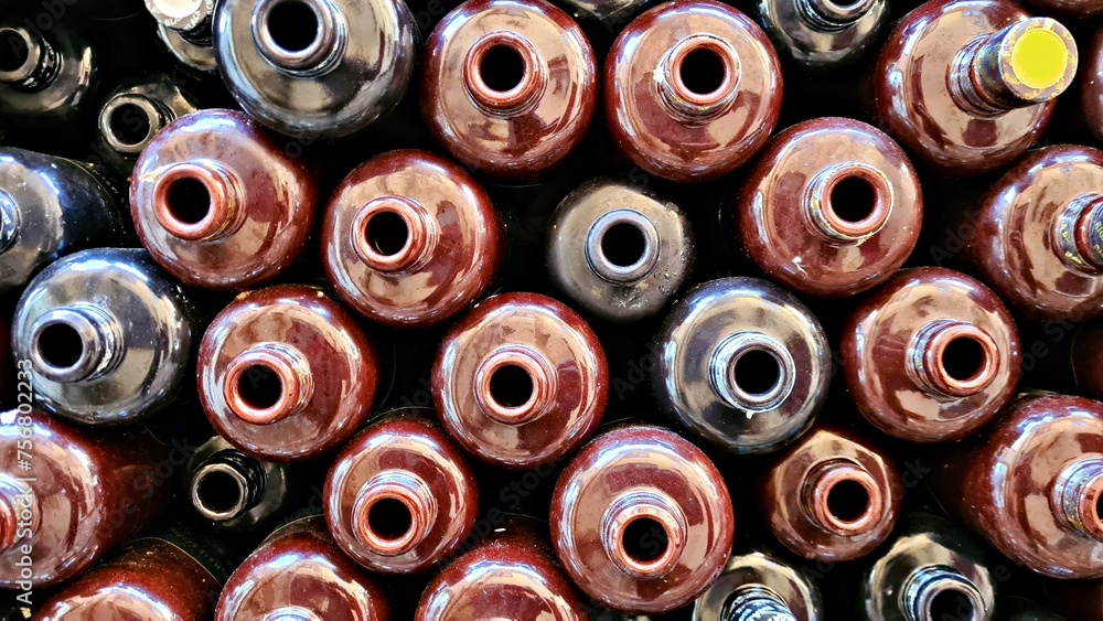 Fototapeta premium Many ceramic empty bottles for alcoholic drink balsam are stacked in wooden cabinet