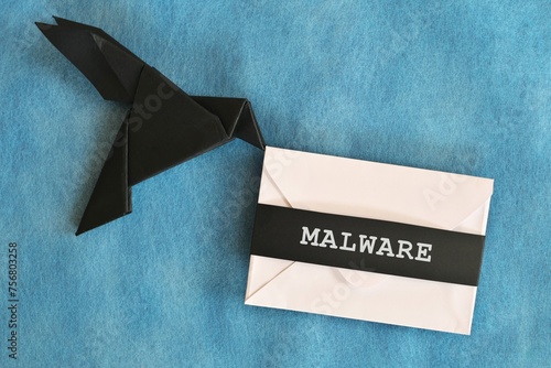Black raven paper origami carrying white letter envelope with word Malware. Receiving malware attack email concept.