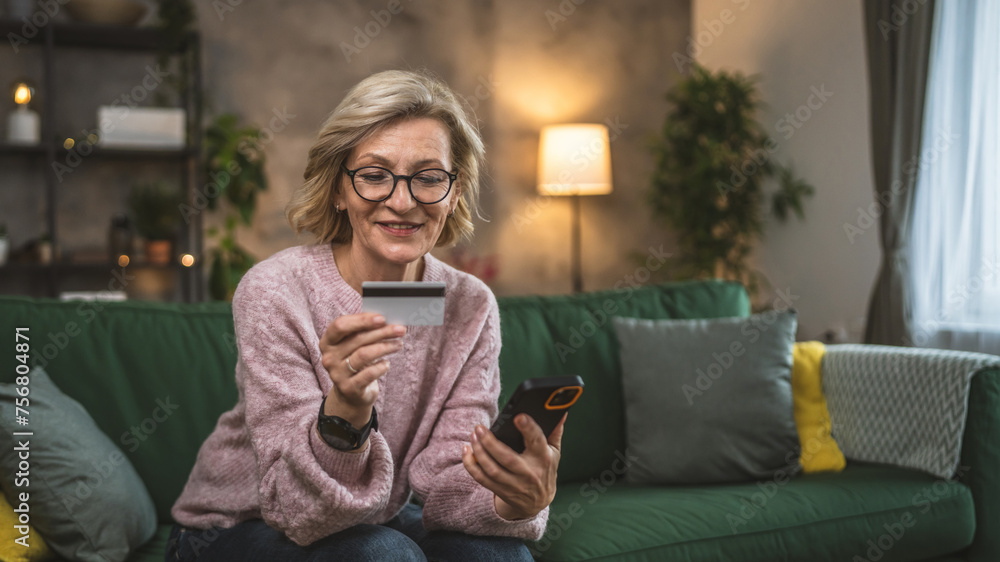 Obraz premium mature woman caucasian female hold credit card online shopping at home