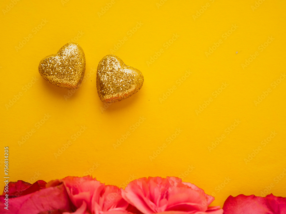 Two gold hearts with glitter and red rose flowers on yellow surface. Flat lay design. Love and romance concept. Copy space for passion message.