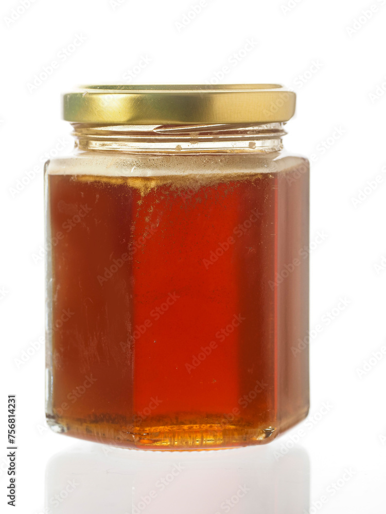 Glass bottle of fine honey with golden lid on white background. Agriculture organic product famous for its sweet taste and health benefits and value. Glass bottle of fine honey with golden lid on white background. Agriculture organic product famous for its sweet taste and health benefits and value.
